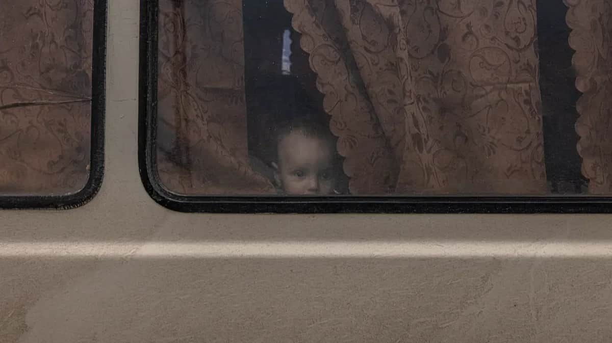 A child looks out of a minibus window in the port city of Henichesk in the Kherson region. Photo: Roman Pilipey / EPA-EFE